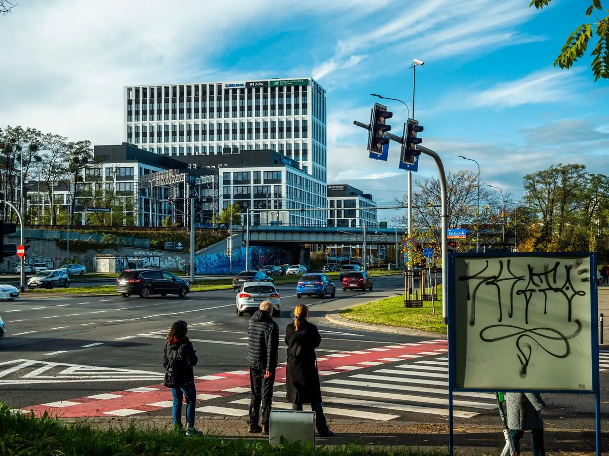 Skrzyżowanie z sygnalizacją świetlną we Wrocławiu, przejście dla pieszych z przejazdem dla rowerzystów oznaczonym na czerwono, piesi czekają na chodniku